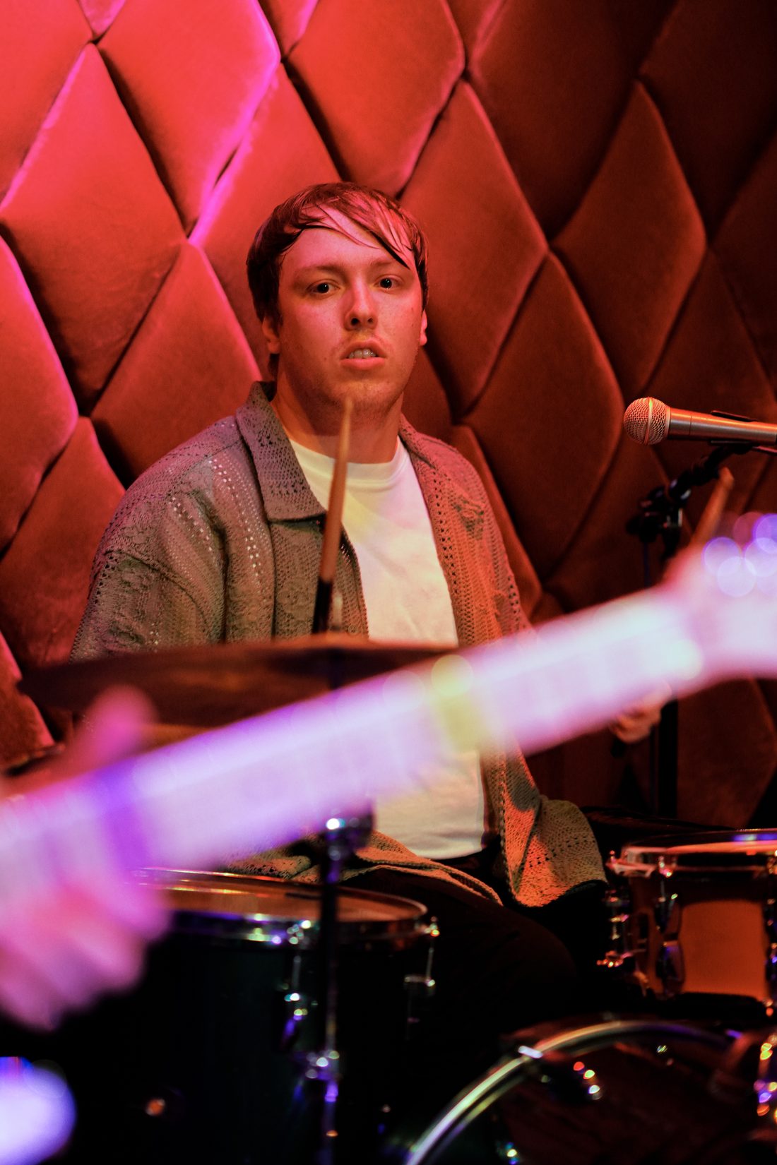 Drummer behind the kit in red venue light